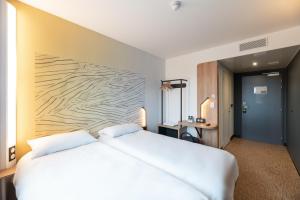 ViriatにあるB&B HOTELS Bourg-en-Bresse Viriatの木製の壁のベッドルーム1室(白い大型ベッド1台付)