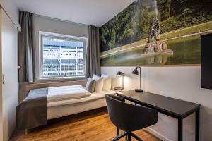 1 dormitorio con cama, escritorio y ventana en KOMPAS Hotel Aalborg, en Aalborg