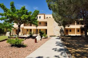 a building with trees and a sidewalk in front of it at Hotel Bartaccia in Propriano