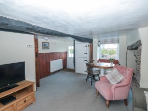 a living room with a tv and a table with a chair at Jean's Cottage in Exeter