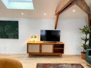 a living room with a flat screen tv on a cabinet at Suite Théodore - 2 pers in Charleville-Mézières +3 photos