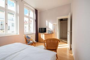 a bedroom with a bed and two chairs and a television at Villa Luna in Ahlbeck