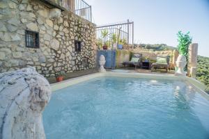 a large swimming pool in front of a stone building at 4 bedrooms villa with private pool furnished garden and wifi at Algarinejo in Algarinejo