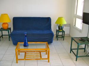 salon z niebieską kanapą i dwoma stołami w obiekcie SUNSET Joli T2 vue mer piscine SUNSET Cap d'Agde w Cap d'Agde