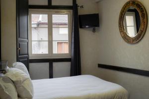 a bedroom with a bed and a mirror and a window at LA FERME D'ANDRE 