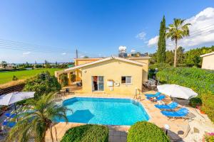 una casa con piscina con sillas y sombrillas en Villa Kampos, en Peyia