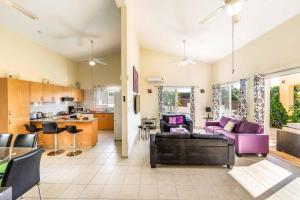 sala de estar con muebles de color púrpura y cocina en Villa Kampos, en Peyia