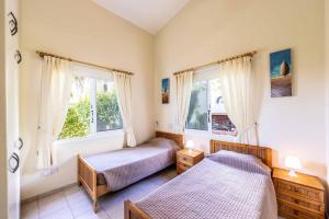 Un dormitorio con dos camas y dos ventanas. en Villa Kampos, en Peyia 30 fotos más