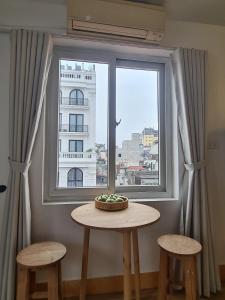 a table and two stools in front of a window at Hanoi All Nations Homestay in Hanoi