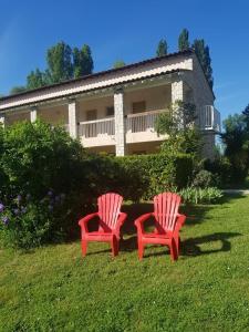 two red chairs sitting in the grass in front of a house at Le Moulin de César in Vaison-la-Romaine
