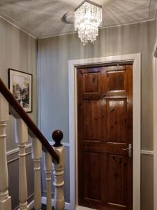 a hallway with a wooden door and a chandelier at Brads Pad -Ballymena Central- in Ballymena