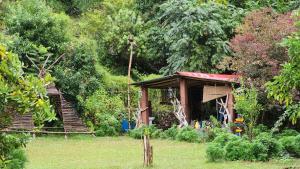 a small building with a staircase in a garden at Hobo Rivercamp in Almora