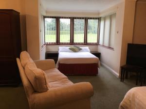 a bedroom with a bed and a couch and a window at Clare House in Mundford
