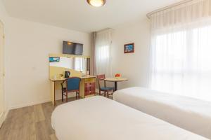 ein Hotelzimmer mit 2 Betten, einem Tisch und Stühlen in der Unterkunft Appart'City Classic Lyon Villeurbanne in Villeurbanne