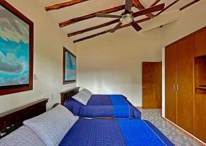 Schlafzimmer mit einem blauen Bett und einem Deckenventilator in der Unterkunft Hotel Finca Del Café in Santa Rosa de Cabal