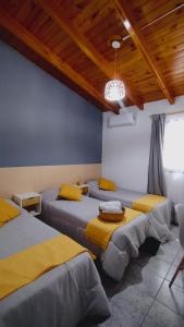 a room with four beds with yellow sheets and a wooden ceiling at Hotel Alta Mendoza in Mendoza