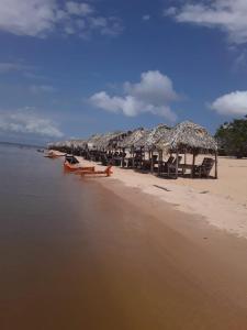 een strand met een stel rieten parasols en stoelen bij Pousda kurasi alter in Alter do Chao