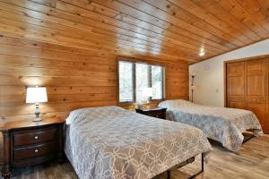 two beds in a room with wooden walls at Bark Point Retreat in Herbster