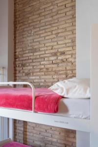 バレンシアにあるパープル ネスト ホステルの白い二段ベッド(レンガ壁)