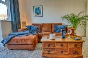 een woonkamer met een bruine leren bank en een tafel bij GORNAL DUDLEY 2 Bed, EXEC Traveller & CONTRACTOR stays in Gornalwood