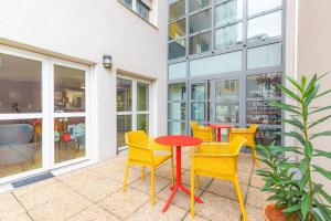 un patio con sillas amarillas y una mesa roja en Appart'City Classic Lyon Villeurbanne en Villeurbanne