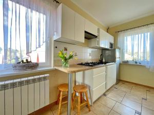 a kitchen with white cabinets and a counter with stools at TOPOLA in Gąski