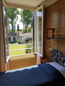 een slaapkamer met een bed en een groot raam bij Le Moulin de César in Vaison-la-Romaine