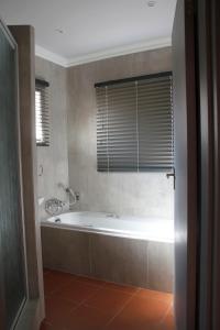 uma banheira na casa de banho com uma janela em Vita Nova em Bloemfontein