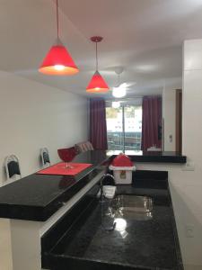 una cocina con encimera negra y 2 luces rojas en lindo apartamento de 1 quarto com vista para o mar, en Arraial do Cabo