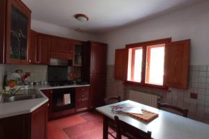 une cuisine avec des placards en bois, une table et une fenêtre dans l'établissement Casa Pie' di Monte, à Bisegna
