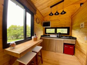 una cocina en una cabaña de madera con encimera y ventanas en El Hostel Granjero, en Sesquilé