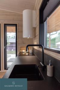 uma cozinha com um lavatório e uma janela em Hirsihuvila Villa Letto, pihasauna & ulkoporeamme em Kalajoki