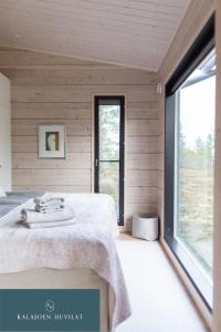 ein Schlafzimmer mit einem Bett und einem großen Fenster in der Unterkunft Hirsihuvila Villa Letto, pihasauna & ulkoporeamme in Kalajoki