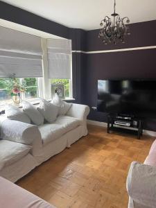 a living room with a white couch and a flat screen tv at Pet friendly unique 4-Bed Bungalow in Porthcawl in Porthcawl