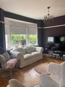 a living room with a white couch and a tv at Pet friendly unique 4-Bed Bungalow in Porthcawl in Porthcawl