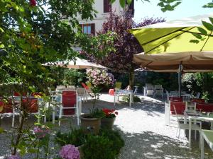 un jardín con mesas, sillas y una sombrilla en Hôtel Gallia en Aix-les-Bains