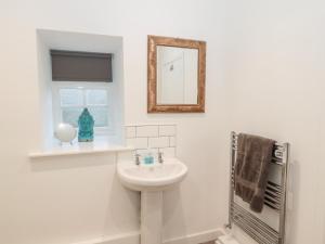 a white bathroom with a sink and a mirror at Flodden in Cornhill-on-tweed