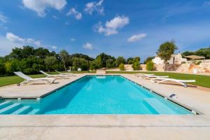 an outdoor swimming pool with lounge chairs and a swimming poolvisor at white moon holiday home in Ostuni