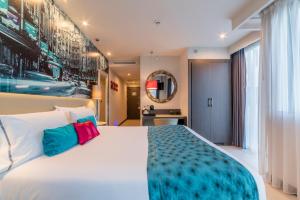 a bedroom with a large white bed with colorful pillows at Hotel Indigo Madrid - Gran Vía by IHG in Madrid