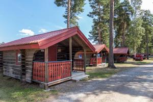 une cabane en rondins avec un toit rouge et une terrasse couverte dans l'établissement First Camp Siljansbadet - Rättvik, à Rättvik