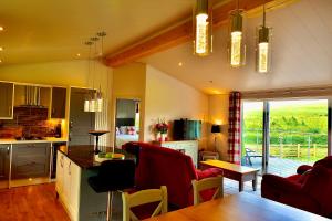a kitchen and living room with red chairs and a table at Arbennig Luxury Lodges in Mold