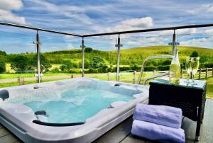 eine Whirlpool-Badewanne auf einer Terrasse mit Aussicht in der Unterkunft Arbennig Luxury Lodges in Mold