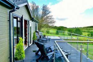a deck with two chairs and a table on a house at Arbennig Luxury Lodges in Mold