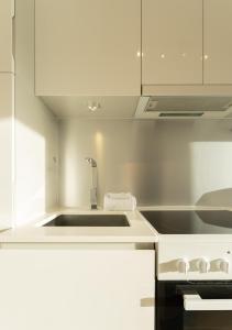 托爾斯港的住宿－Stylish Aparthotel in Tórshavn，白色的厨房设有水槽和炉灶。
