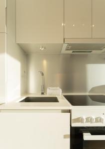a white kitchen with a sink and a stove at Stylish Aparthotel in Tórshavn in Tórshavn