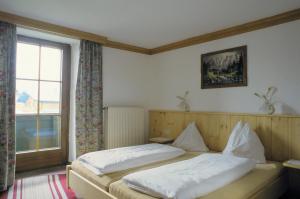 een slaapkamer met 2 bedden en een raam bij Kaiserpension Müllnerhof in Oberndorf in Tirol