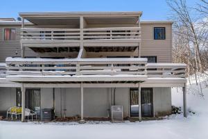 a building with a large deck in the snow at Hideaway Valley Condo 36 in Harbor Springs