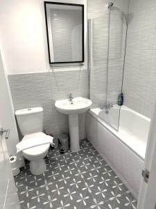 a bathroom with a sink and a toilet and a bath tub at Thorpe House - Home Crowd Luxury Apartments in Doncaster