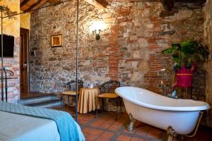 a bedroom with a bath tub in a brick wall at Luxury Corte Di Re Artù in Lucca