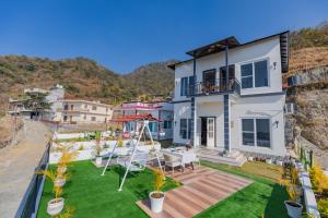 a house with a balcony with a lawn at SaffronStays Niyama, Dehradun in Dehradun